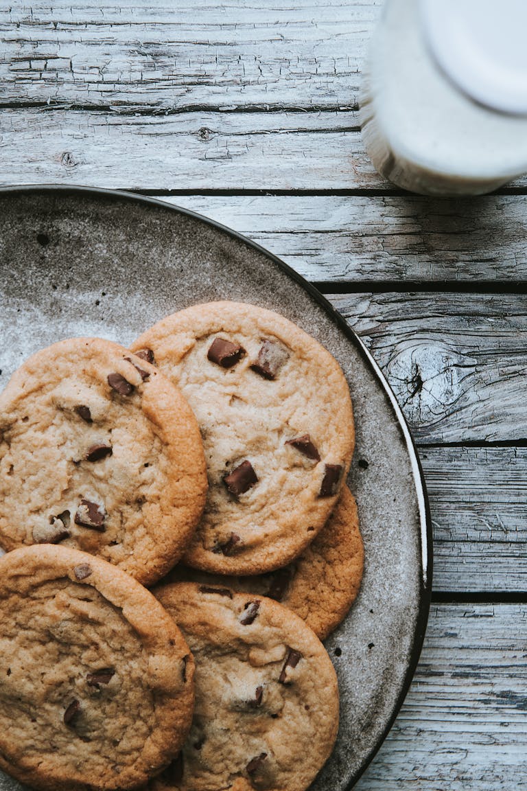 Delicious homemade chocolate chip cookies arranged on a rustic wooden table with a glass of milk.