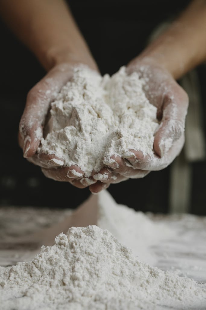Close-up of a person holding freshly milled flour in their hands inside a kitchen.