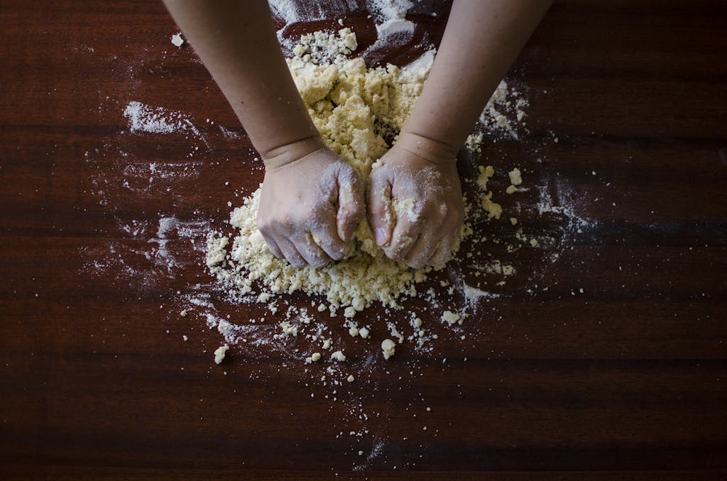 Close-up of hands kneading dough for baking on a wooden table, ideal for cooking themes.