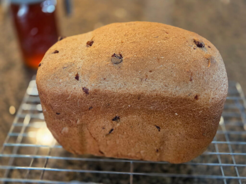 Cinnamon raisin bread on cooling rack with honey in the background