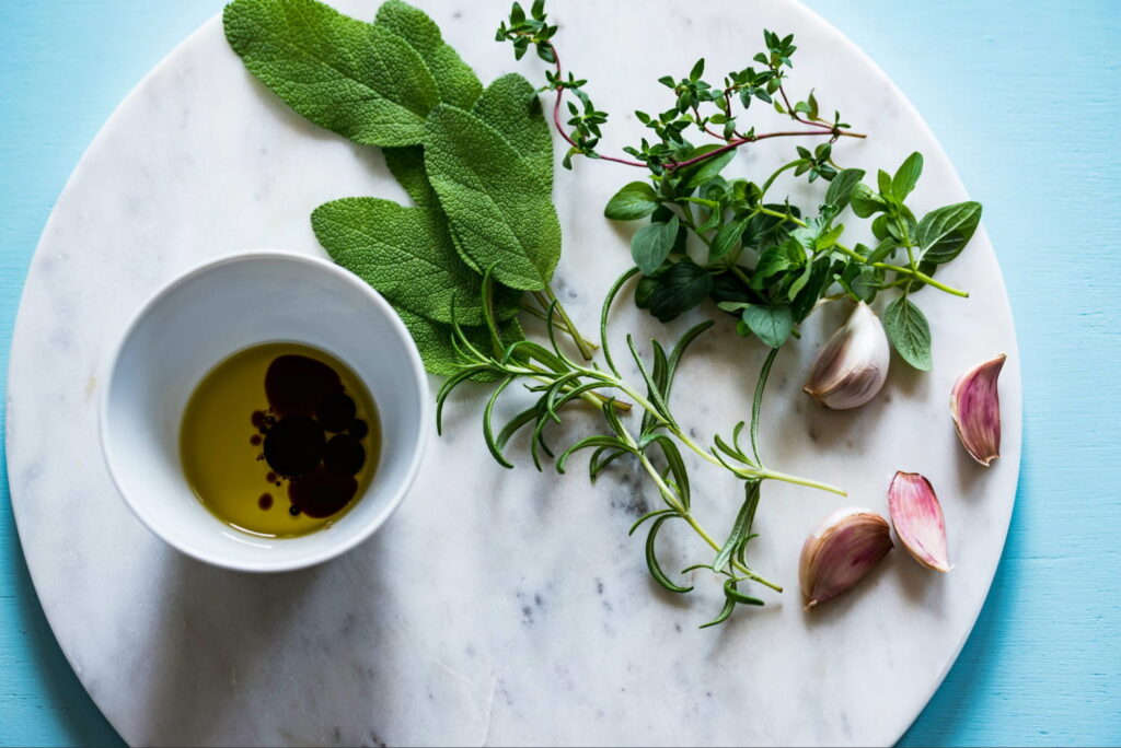 Fresh herbs next to bowl of oil and vinegar