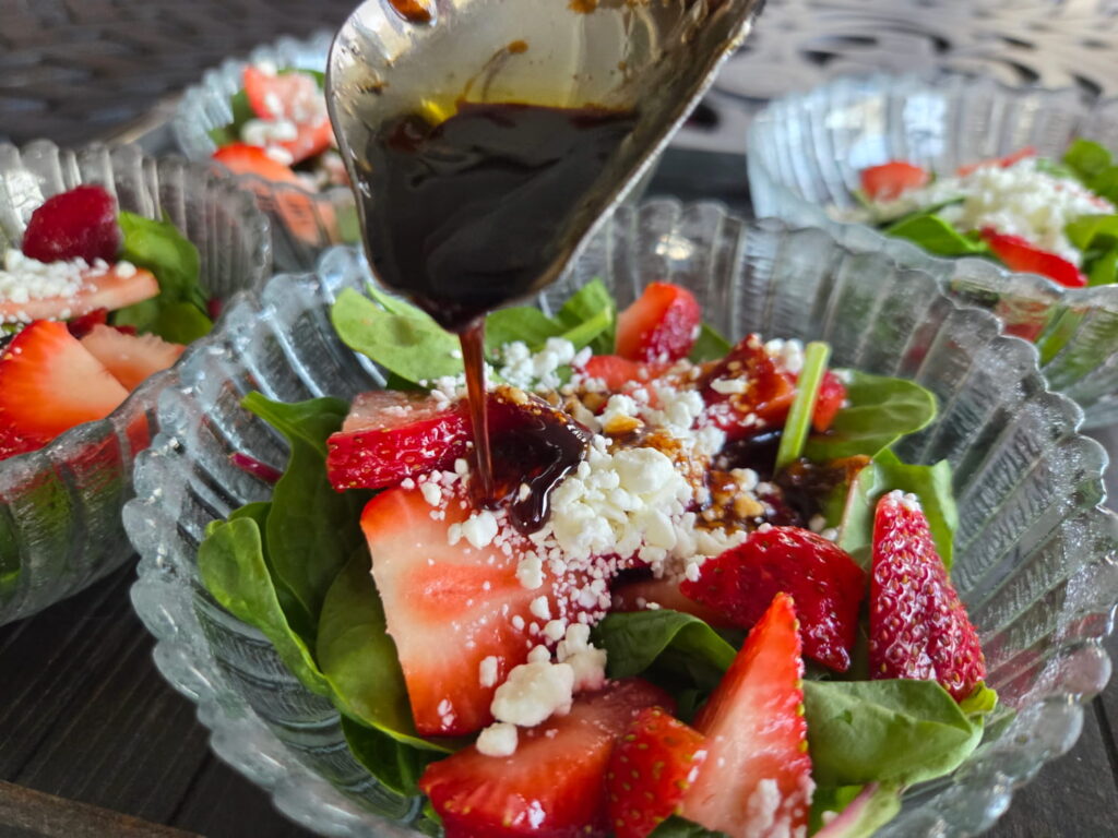 strawberry spinach salad with balsamic dressing pouring on it